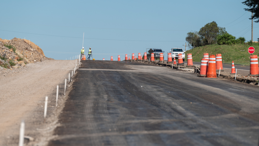 Rodovia em construção, com cones laranjas nas margens da estrada.
