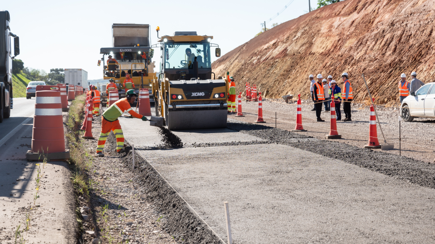 Construção de uma rodovia, com maquinário trabalhando e pessoas uniformizadas.