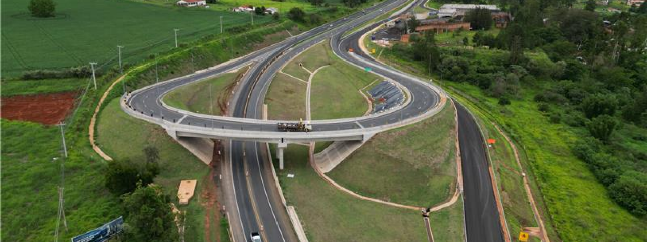 Perspectiva aérea de uma rodovia com destaque ao contorno viário, com veículos trafegando.