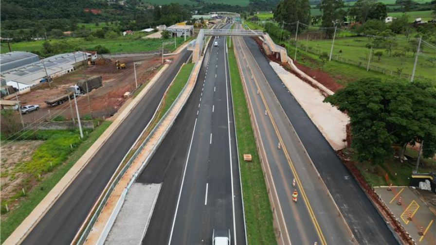 Perspectiva aérea de uma rodovia, com obras e a infraestrutura em desenvolvimento as margens da rodovia e com pavimento novo.