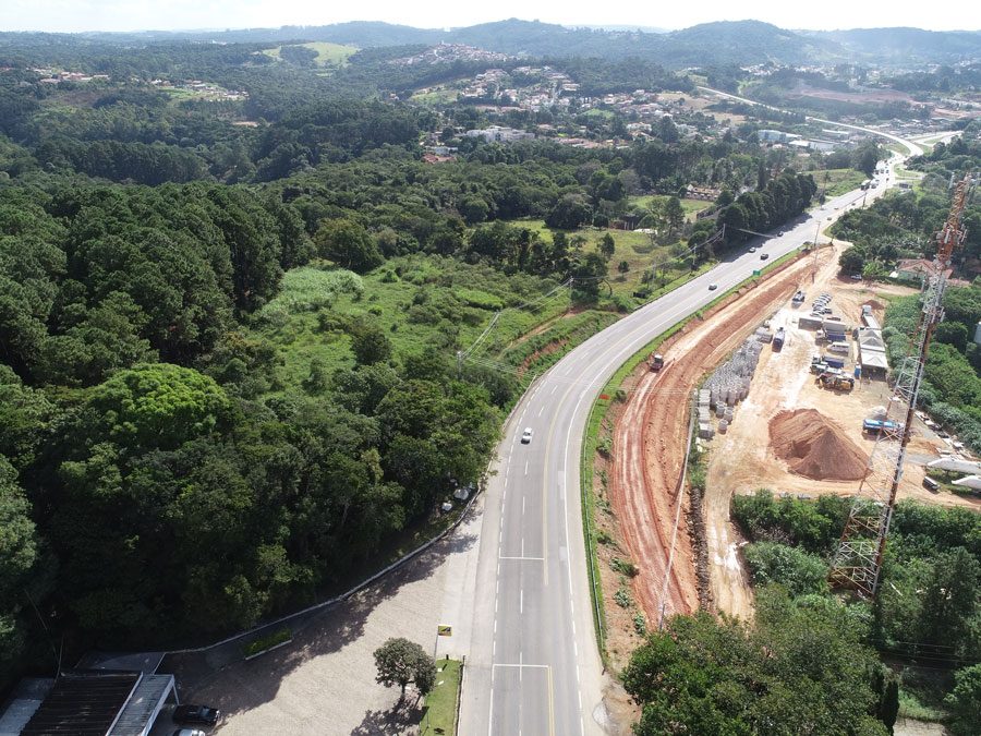 Perspectiva aérea da construção de uma estrada, com obras e a infraestrutura em desenvolvimento as margens da rodovia.