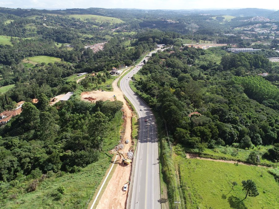 Perspectiva aérea da construção de uma estrada, com obras e a infraestrutura em desenvolvimento as margens da rodovia.