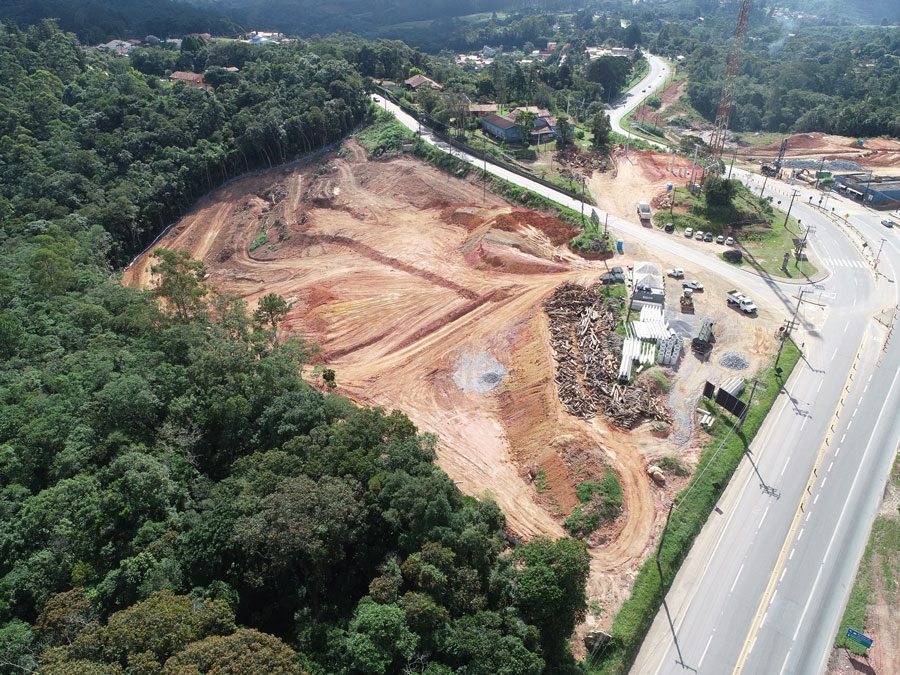 Perspectiva aérea da construção de uma estrada, com obras e a infraestrutura em desenvolvimento as margens da rodovia.