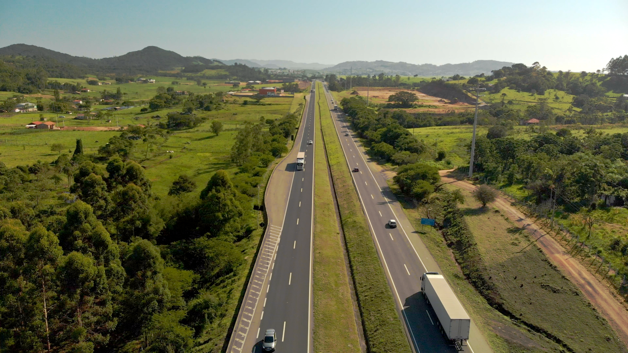 Rodovia de mão dupla, administrada pela CCR Via Costeira, com vegetação nas margens.